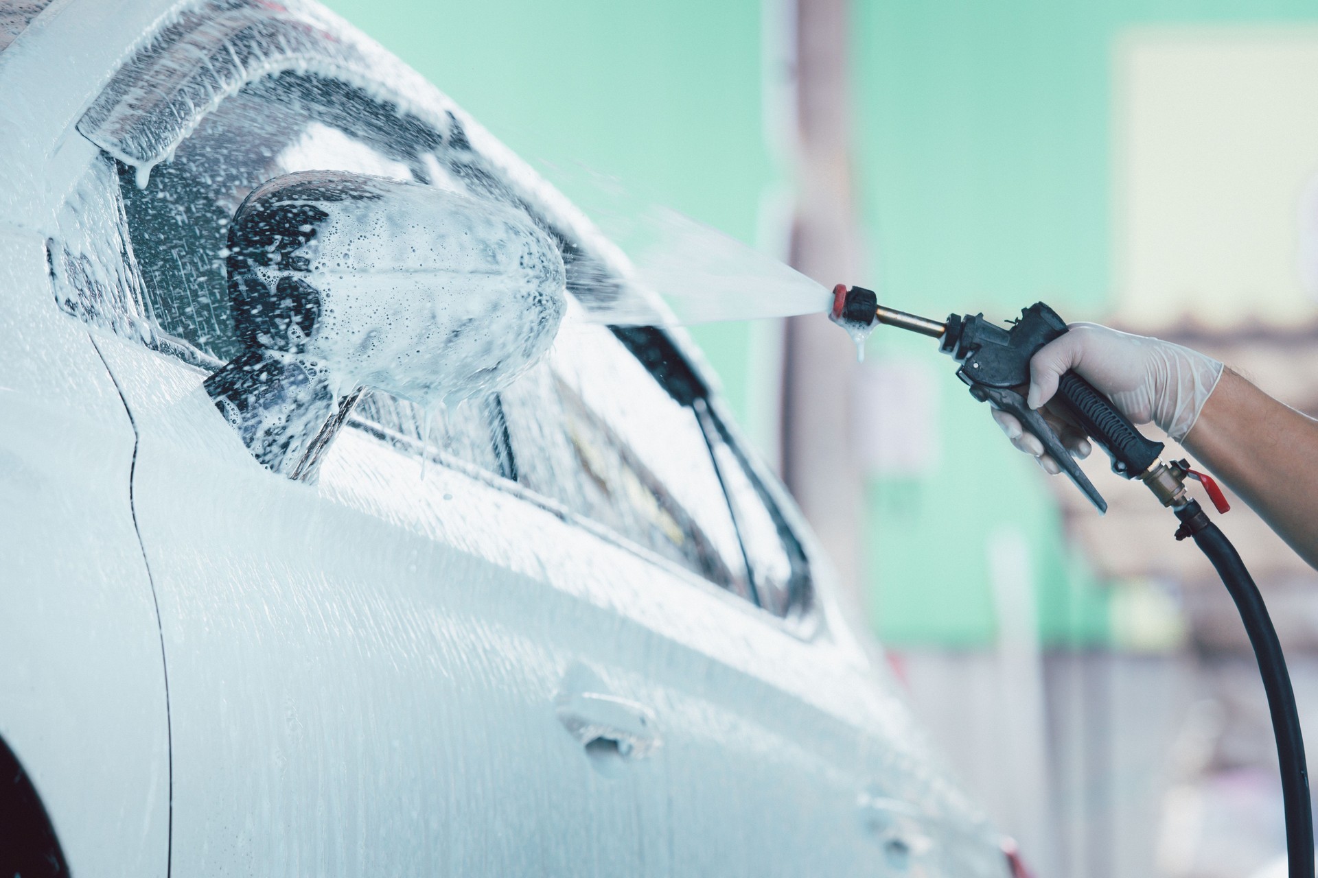 Man spraying a soap foam on the vehicle.